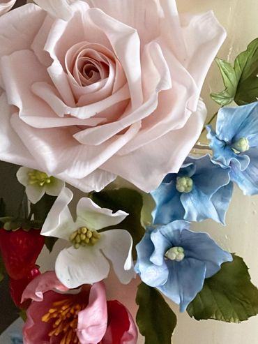 Close up of pale pink roses, white apple blossom, blue hydrangeas, strawberries.