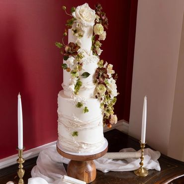 Whimsical white wedding cake with sugar roses, claret hellebores and green hydrangeas.