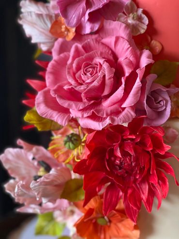 Close up of sugar flowers - bright pink roses, red dahlia, orange and pink tulips.