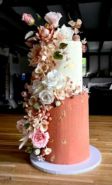 Two tier ganached cake,  burnt orange stencilled bottom tier and cascading sugar flowers & gold leaf.