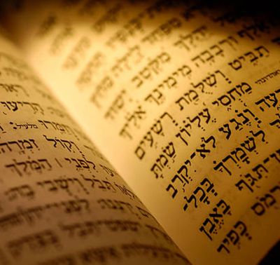 Close-up of Hebrew text on an aged, illuminated manuscript.