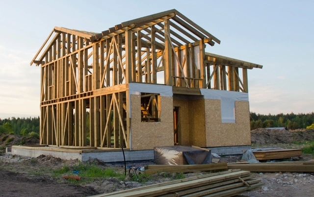 Wooden frame of a house under construction in a rural area.