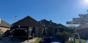 Workers repairing a roof under clear blue sky on a sunny day.