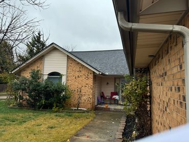 Cozy brick house with a small front porch and chairs on a cloudy day.