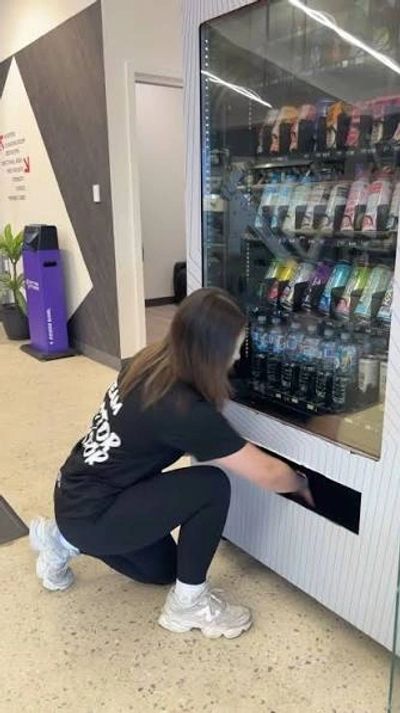 Person retrieving an item from a vending machine.