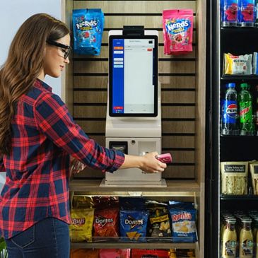 Woman uses a self-checkout kiosk at a snack and beverage store.
