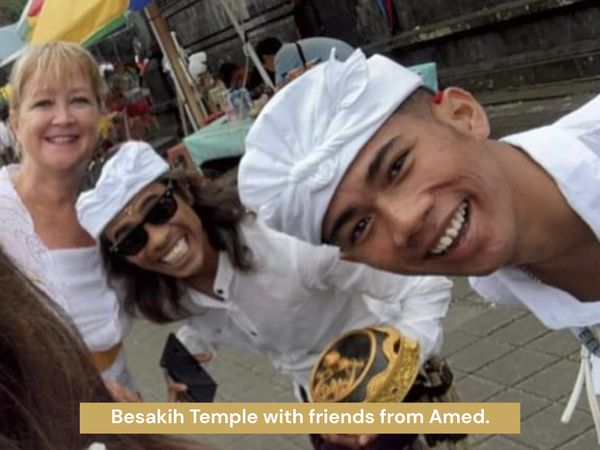 Balinese and tourist wearing ceremonial clothes pose for a picture at Besakiih Temple in Bali.