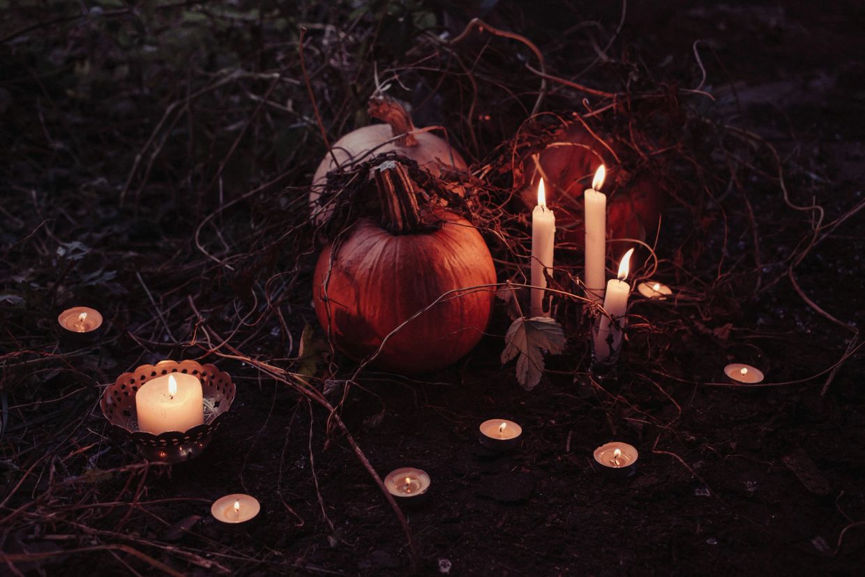 Calabazas y velas encendidas en un ambiente oscuro.