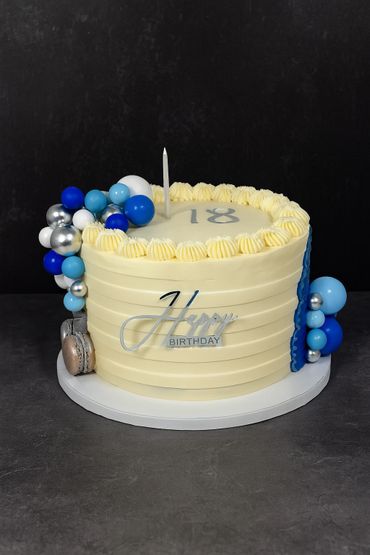 Elegant 18th birthday cake with blue, silver balloons and a macaroon decoration.