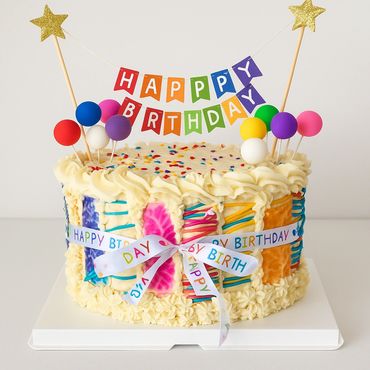 Colorful birthday cake with balloons and a banner.