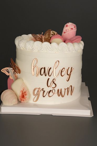 Elegant white cake with pink and gold decorations celebrating Hayley's growth.