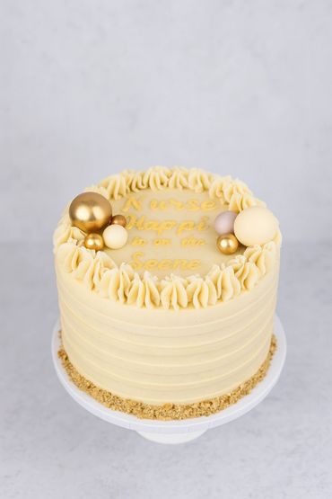 Elegant cream cake with gold and pearl decorations on top.