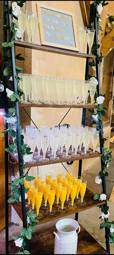 A decorated shelf with champagne and orange juice glasses for a wedding celebration.
