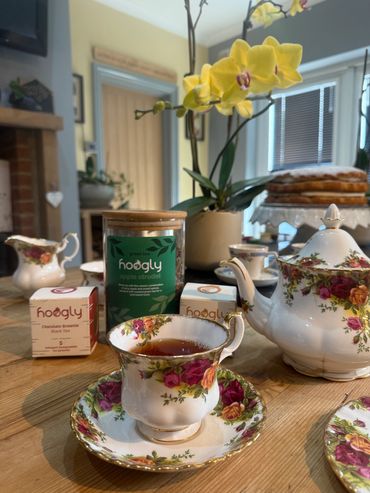 Elegant floral tea set with Hoogly tea and yellow orchids on a wooden table.