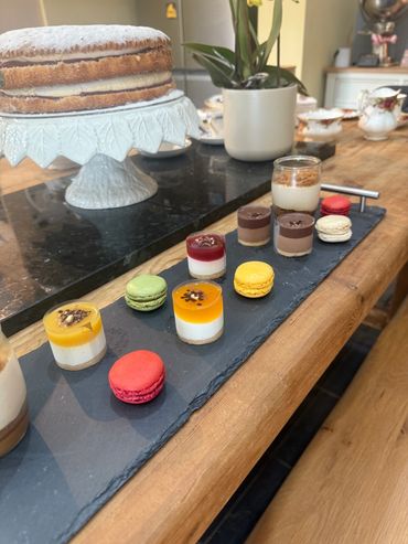 A variety of colorful macarons and mini desserts on a slate tray.
