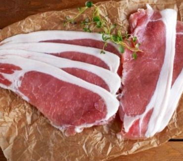 Fresh raw pork chops with herbs on brown paper.