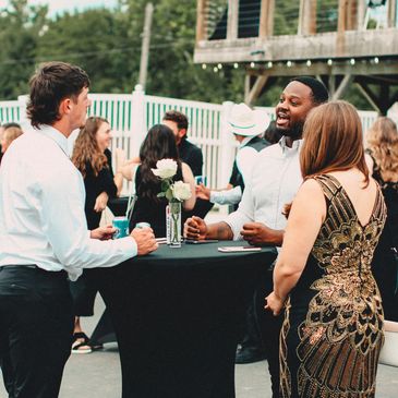 Small event with multiple people conversing at a tall table with friends.