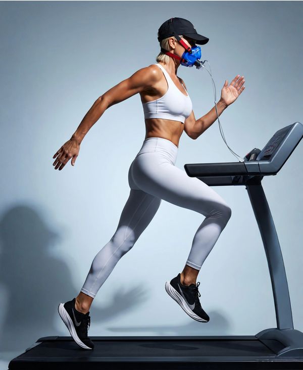Athletic woman running on treadmill with an oxygen mask for fitness testing.