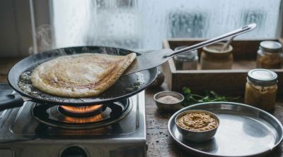 Cooking Upwas dosa on a stovetop griddle.