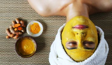 Person with a turmeric face mask and towel wrapped around head.
