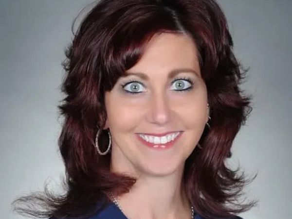 Smiling woman with red hair and blue eyes.