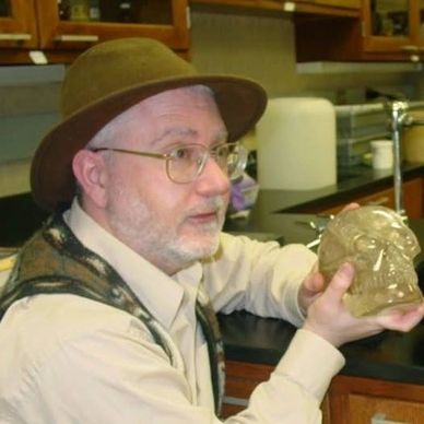 Man in hat holding a crystal skull.