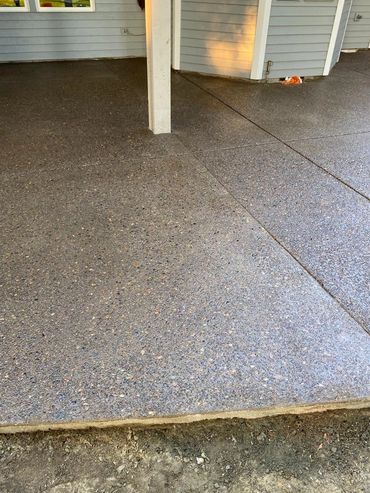 Newly finished exposed aggregate concrete patio outside a house.