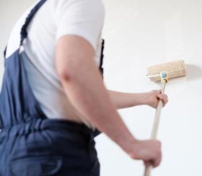 Person painting a wall with a roller brush.