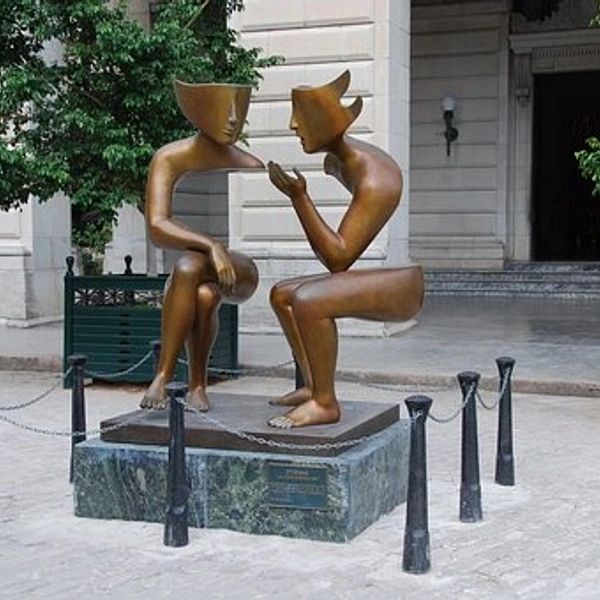Abstract bronze sculpture of two seated figures engaged in conversation.