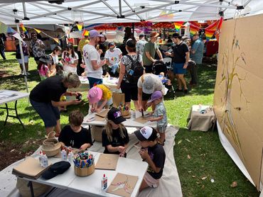 Children and adults engage in arts and crafts under a canopy at an outdoor event.