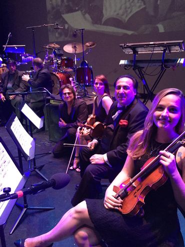 Group of people sitting together and playing violin