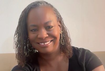 Smiling woman with curly hair and hoop earrings.