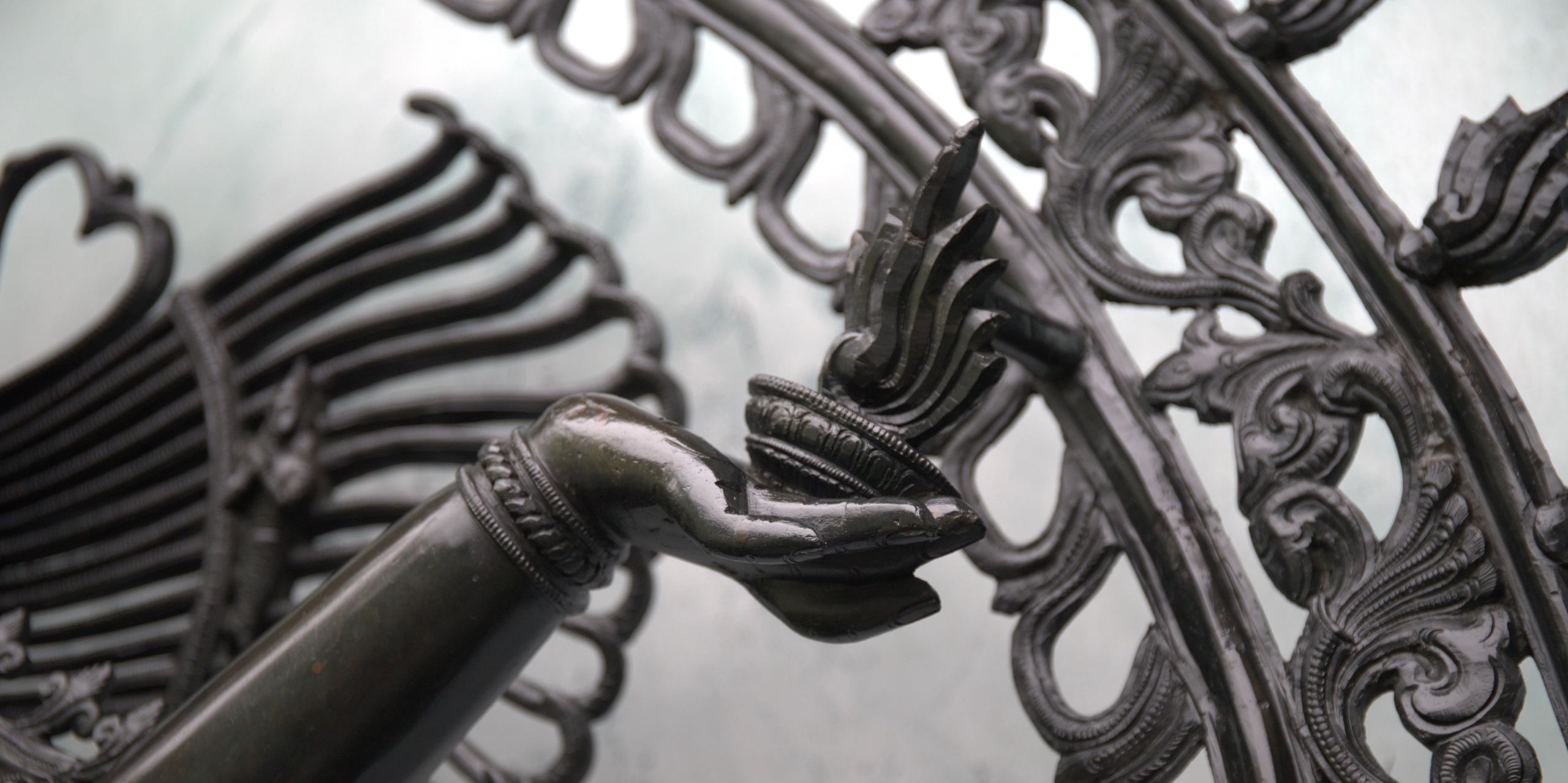 Intricate bronze statue of Nataraj hand holding flame, with ornate patterns & traditional design.