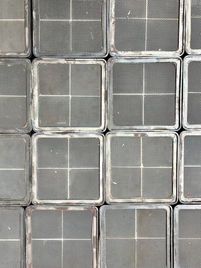 Rows of square metal grates with cross patterns.