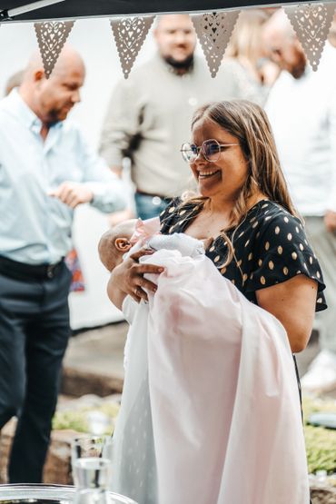 Mutter hält ihr Baby liebevoll bei der Taufe im Arm
