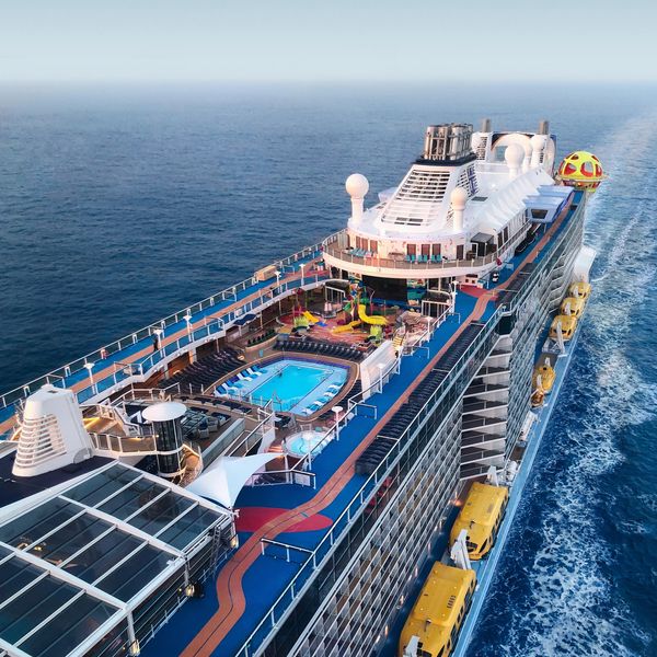 A large cruise ship with pool sailing on the ocean.
