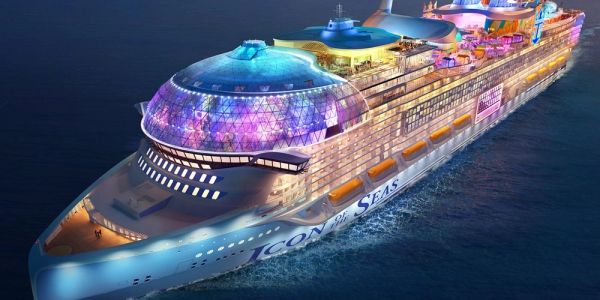 A large brightly lit cruise ship named Icon of Seas at night.