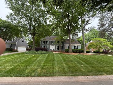 Large two-story house with gray siding and a manicured lawn.