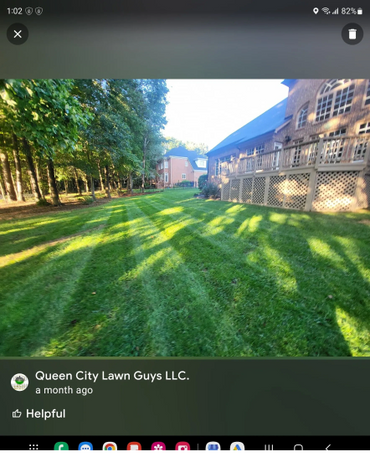 Sunlit backyard with fresh lawn stripes beside a large brick house.