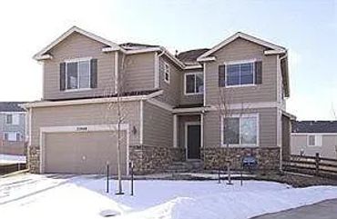 Two-story suburban house with snow-covered yard and attached garage.