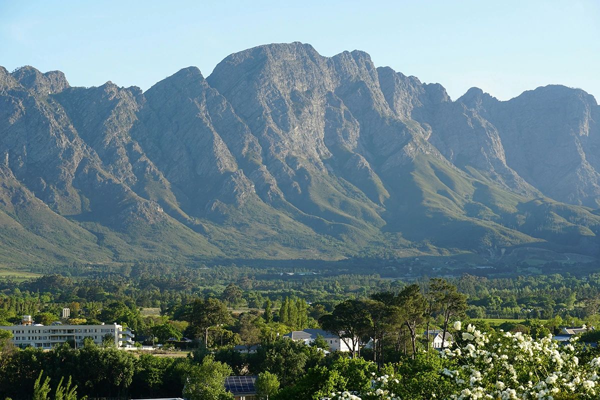 Dramatic Franschhoek mountain peaks with vineyards and fynbos in foreground, essential Cape Winelands day trip from Cape Town