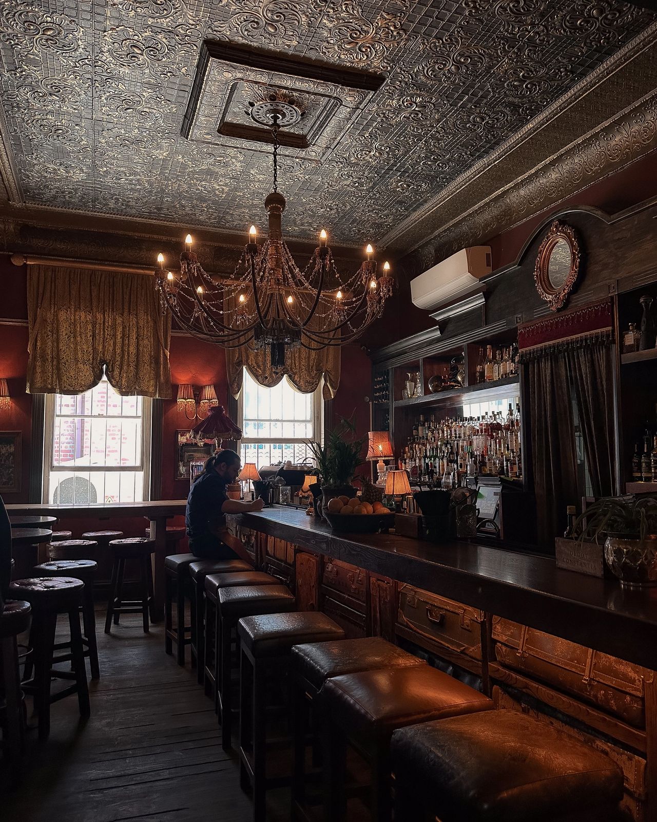 Our Local Cape Town interior featuring ornate pressed-tin ceiling, crystal chandelier, and moody vintage bar atmosphere