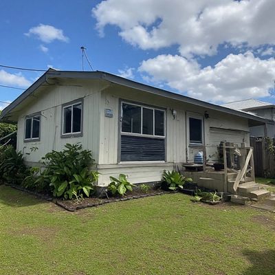 Small single-story house with white exterior and green lawn.
