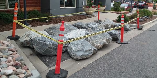 Boulders staged to be installed in commercial courtyard, roped off for safety. 