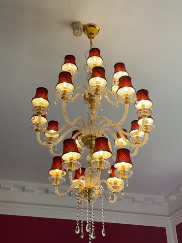 Elegant chandelier with red lampshades and crystal accents.