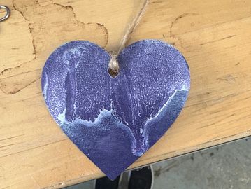 A purple heart-shaped ornament with a textured surface on a wooden table.