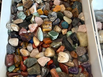 A collection of polished multicolored stones in a white container.