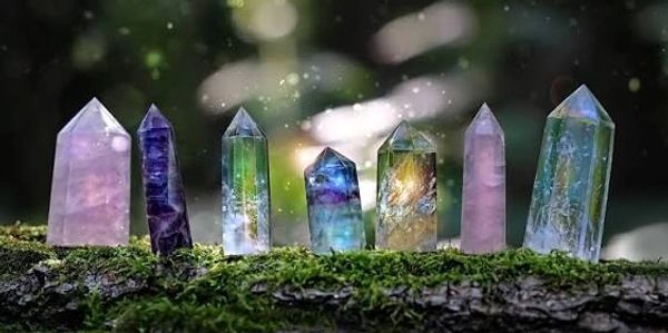 Colorful crystal points glowing on mossy log in soft sunlight.