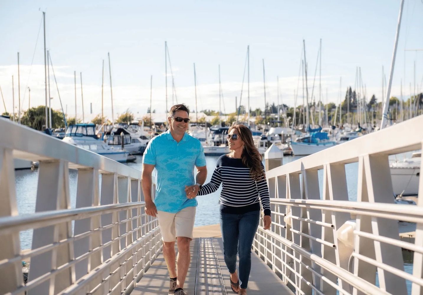 A couple walking up the boat dock of a marina