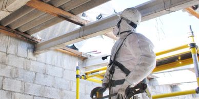 Worker in protective gear using bolt cutters on construction scaffolding.